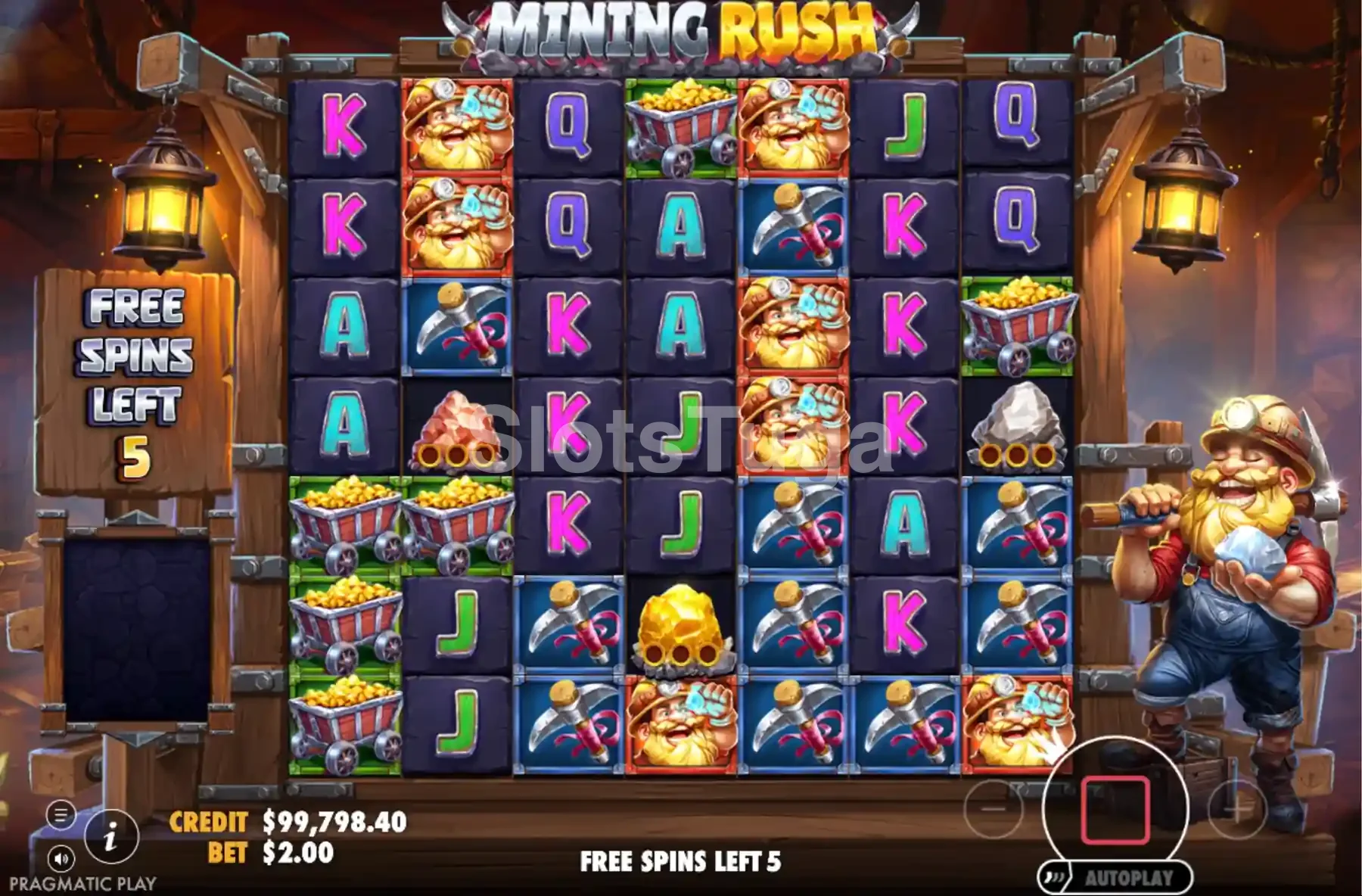 As rodadas grátis de Mining Rush: grelha de sete por sete com vagonetas de ouro, anões mineiros de capacete, picaretas, uma pepita dourada e letras de cartas, num túnel de mina iluminado por lanternas, com o mineiro de barba loura à direita a segurar uma pedra.