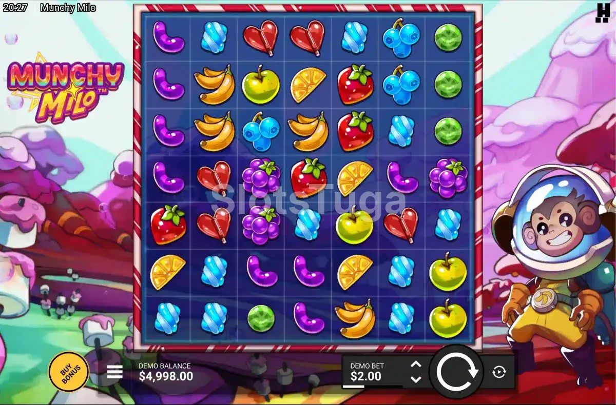 Munchy Milo em jogo base: uma grelha de sete por sete com gomas roxas, rebuçados azuis, corações de chocolate, bananas, mirtilos e morangos, num planeta de algodão doce, e o macaco astronauta Milo de capacete à direita.