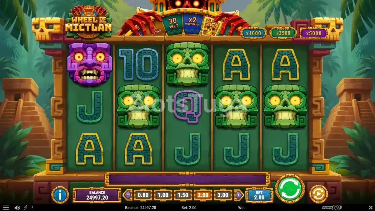 Wheel of Mictlan em jogo base: grelha de cinco por três com caveiras de jade de olhos amarelos, uma máscara roxa e letras de cartas em pedra, a roda dos prémios no topo e os jackpots Mini x1000, Major x2500 e Grand x5000 à direita, entre duas pirâmides na selva.